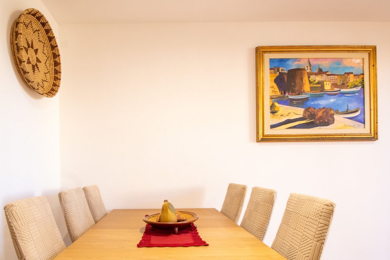 A dining table with a red placemat, a woven basket, and a bowl of fruit.