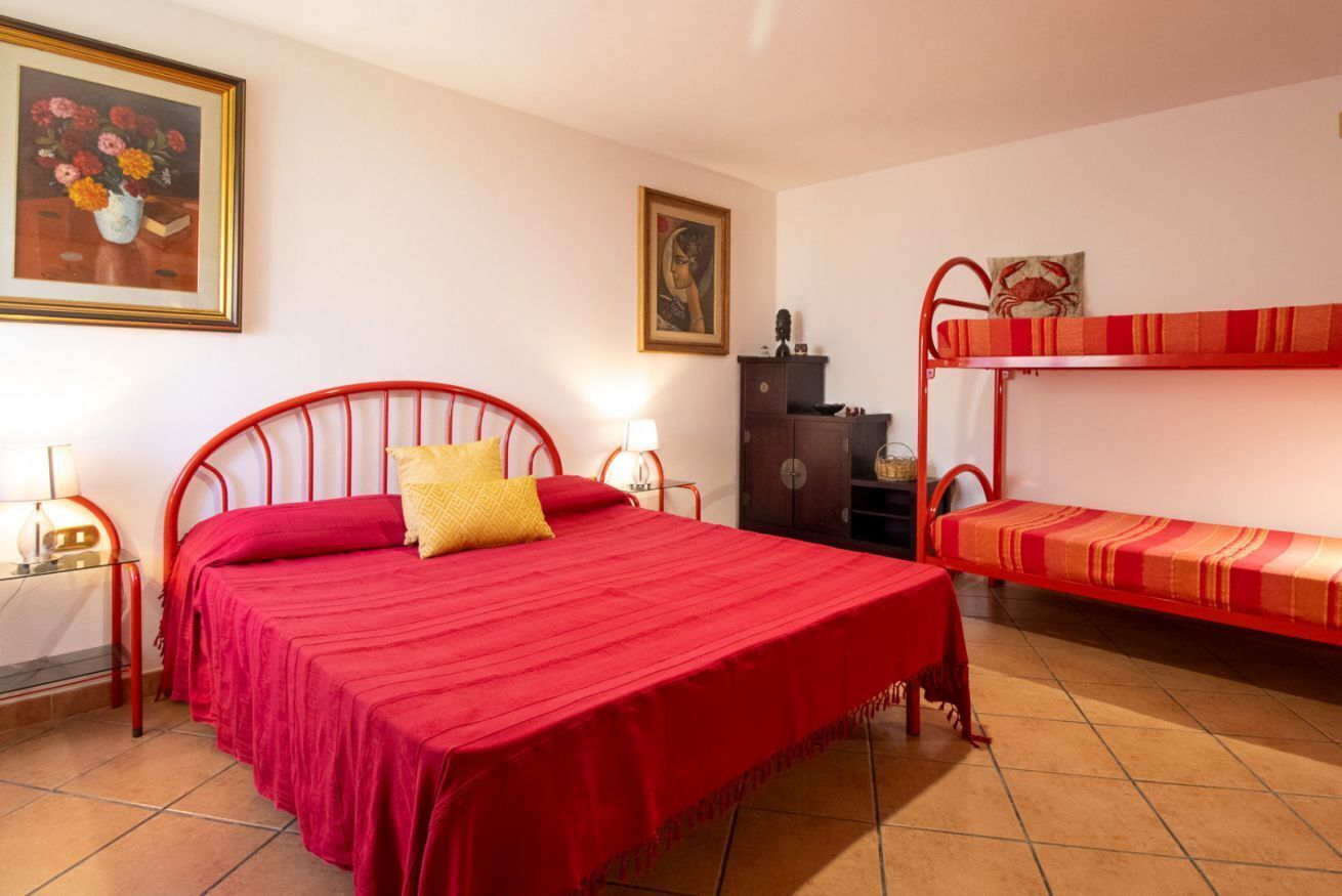 Une chambre avec un lit simple, un lit superposé, une commode et un tableau au mur.