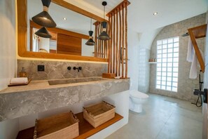 A bathroom with a marble sink, wooden shelves, a large mirror, and a window with a view. - K Club Cemagi Villa 1 (Badung)