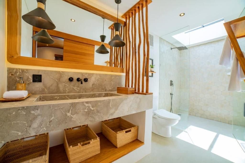 A modern bathroom with a marble sink, wooden accents, and a glass shower enclosure.