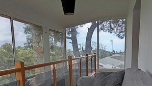A room with a sofa, large windows, and a balcony railing. - Private pool and garden, near the beach, mountain hikes, Port Aventura. (Costa-Cunit)