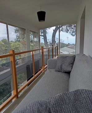 Une pièce avec un canapé, de grandes fenêtres et une balustrade de balcon.