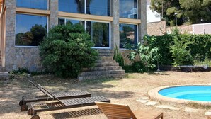 A modern house with large windows, a swimming pool, and outdoor furniture. - Private pool and garden, near the beach, mountain hikes, Port Aventura. (Costa-Cunit)