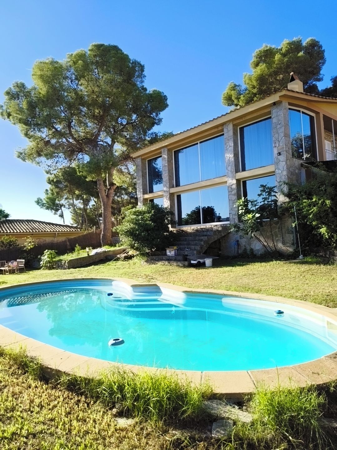 Ein modernes Haus mit Swimmingpool, großen Fenstern und einer Fassade aus Stein.