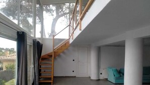 A modern interior with a wooden staircase, large windows, and a teal sofa. - Private pool and garden, near the beach, mountain hikes, Port Aventura. (Costa-Cunit)