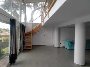 Un intérieur moderne avec un escalier en bois, de grandes fenêtres et un canapé de couleur turquoise.