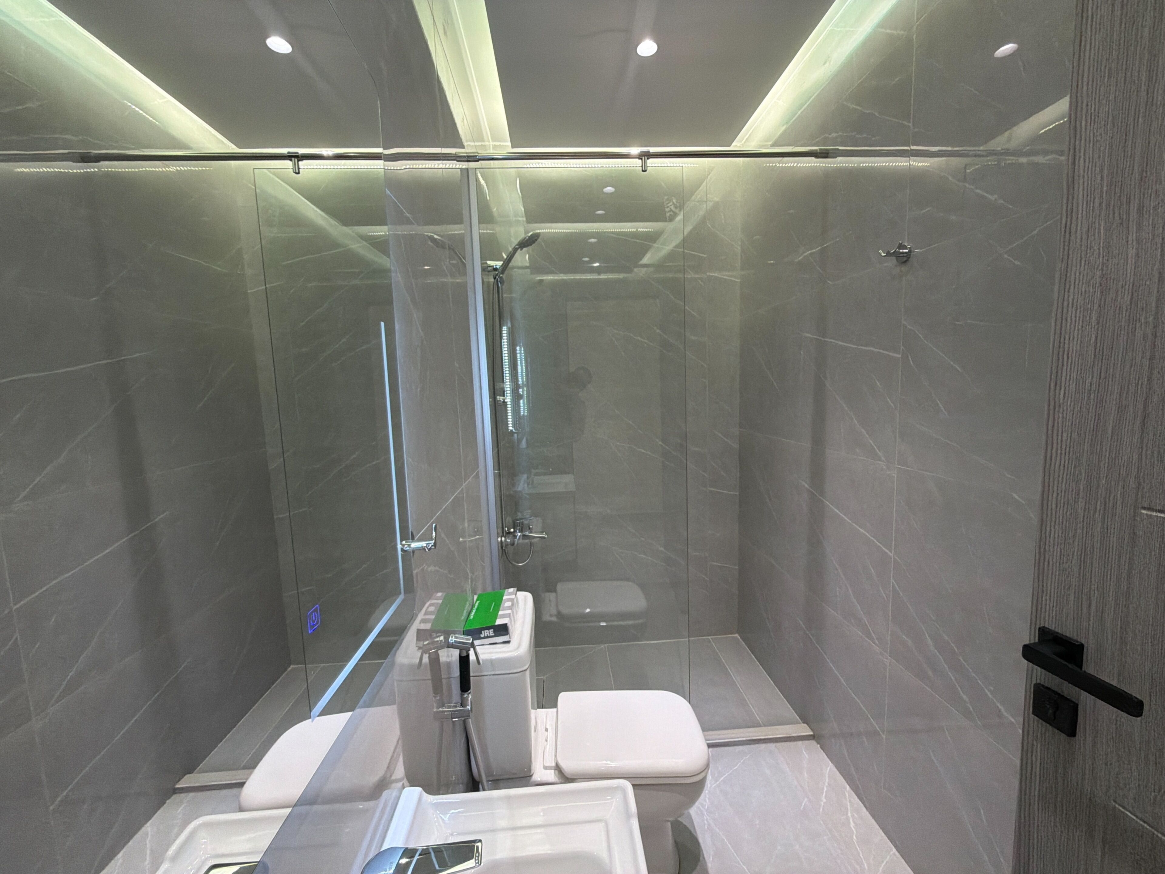 Un bagno moderno con doccia vetrata, un water e un lavandino.