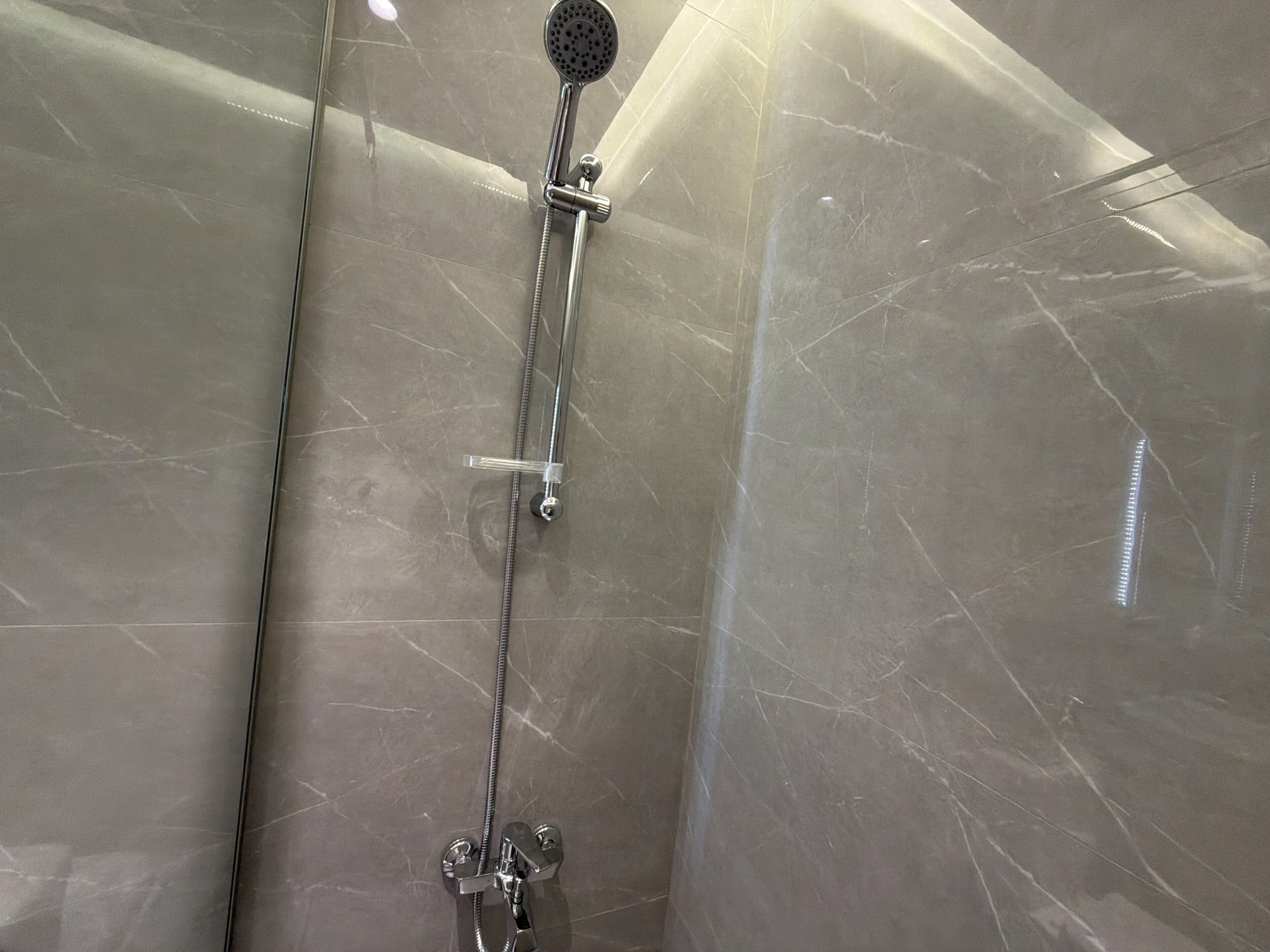 Ducha con cabezal de ducha de mano y llave de control mural.