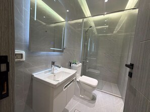Un bagno moderno con doccia vetrata, lavabo bianco e water.