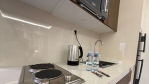 A modern kitchen with a built-in stovetop, a kettle, a sink, and a faucet. - 105 JRE Apartment With Stunning Boulevar (Amman)