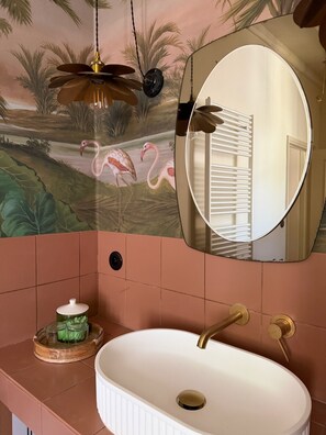 A bathroom with a white sink, a round mirror, a ceiling fan, and a mural of flamingos. - Upmarket "Ame Soeur" B&B room in the center of Chinon (Chinon)