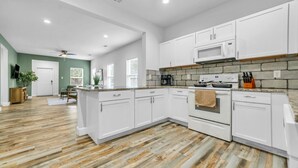 A modern kitchen with white cabinets, a granite countertop, and a built-in oven. - King bed, Double unit, 2 Kitchens | TSD (Rockwall)