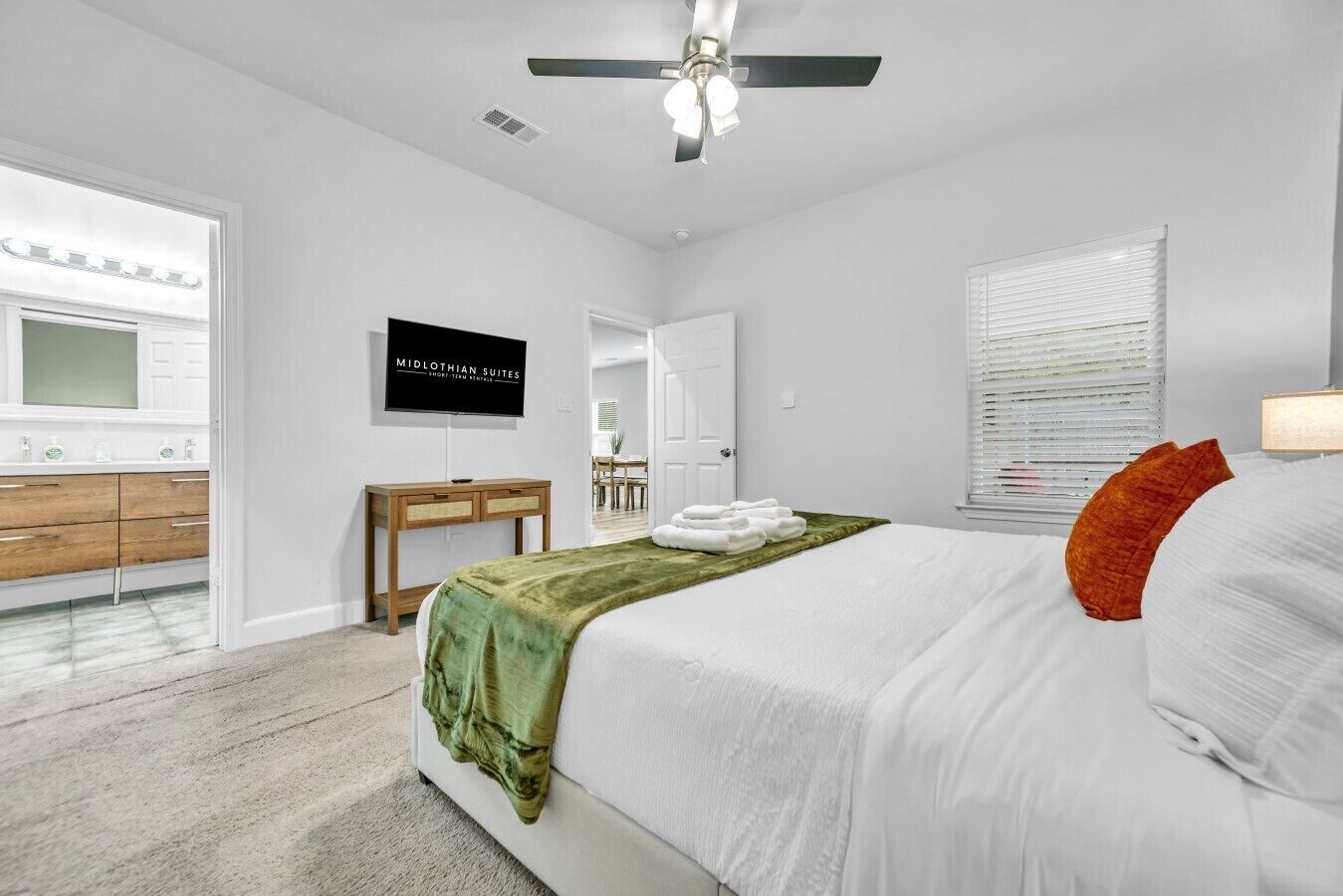 A bedroom with a bed, a desk, a mirror, and a television.
