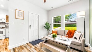A modern living room with a sofa, coffee table, and a dining table. - King bed, Double unit, 2 Kitchens | TSD (Rockwall)