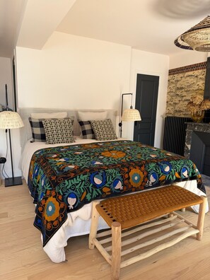 Une chambre à coucher avec un lit, des lampes de chevet, un banc et une tapisserie à motifs.