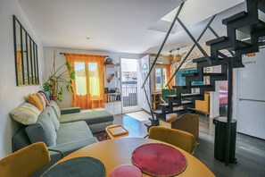 Un salon moderne comprenant un canapé, une table à manger et des chaises, un escalier et un coin cuisine.