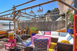 Terraza en la azotea con mobiliario exterior, una mesa y plantas en macetas.