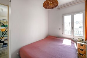 Un dormitorio con cama, ventana, puerta y escalera.