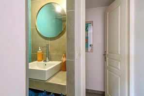 Un baño con lavamanos, espejo y artículos de aseo.