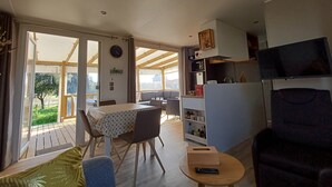 A modern living room with a dining area, a kitchen, and a TV. - Chalet near the sea with garden and shared pool (Talmont-Saint-Hilaire)