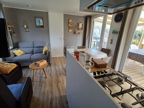 Un espace de vie compact comprenant un canapé, une petite table, un coin cuisine avec une cuisinière à gaz et une table à manger.