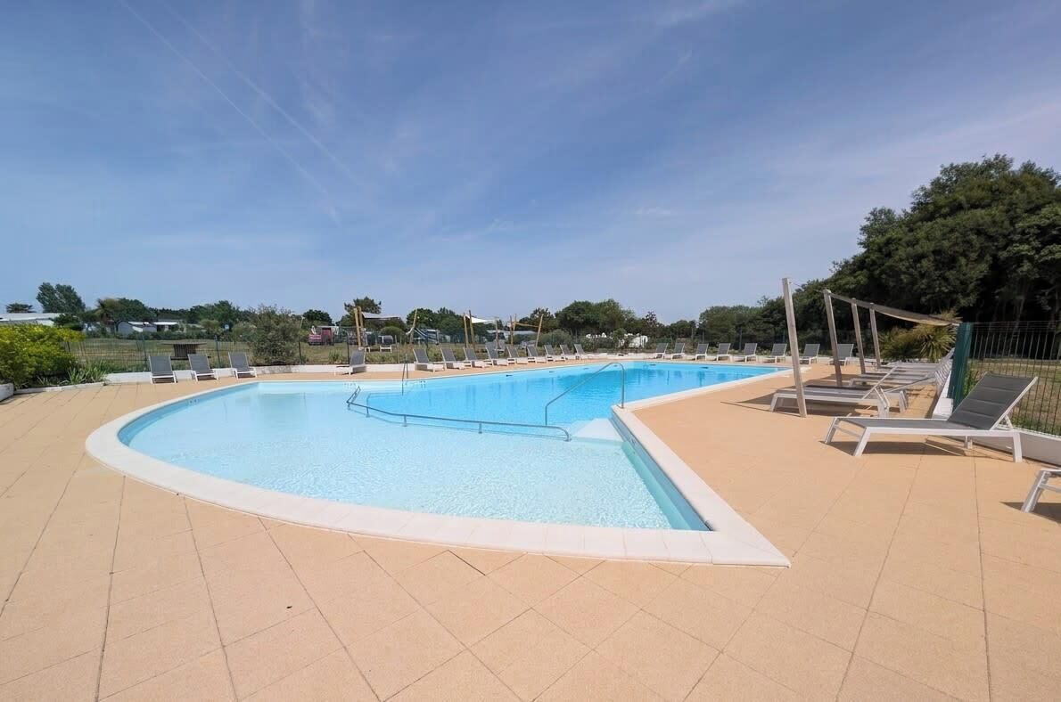 Une grande piscine extérieure dotée de chaises longues et d’une terrasse carrelée.