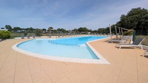 A large outdoor swimming pool with lounge chairs and a tiled deck. - Chalet near the sea with garden and shared pool (Talmont-Saint-Hilaire)