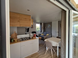 A compact kitchen with a gas stove, wooden cabinets, and a dining area with a table and chairs.