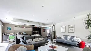 Een moderne woonkamer met een bank, een salontafel en een eethoek, met een keuken op de achtergrond.