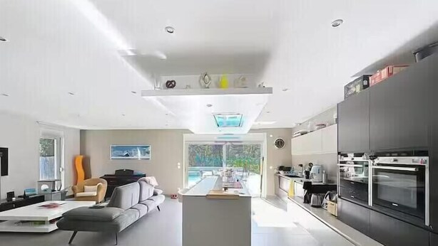 Een moderne keuken met inbouwapparatuur, een zithoek met een bank, en een groot raam dat zorgt voor veel daglicht.