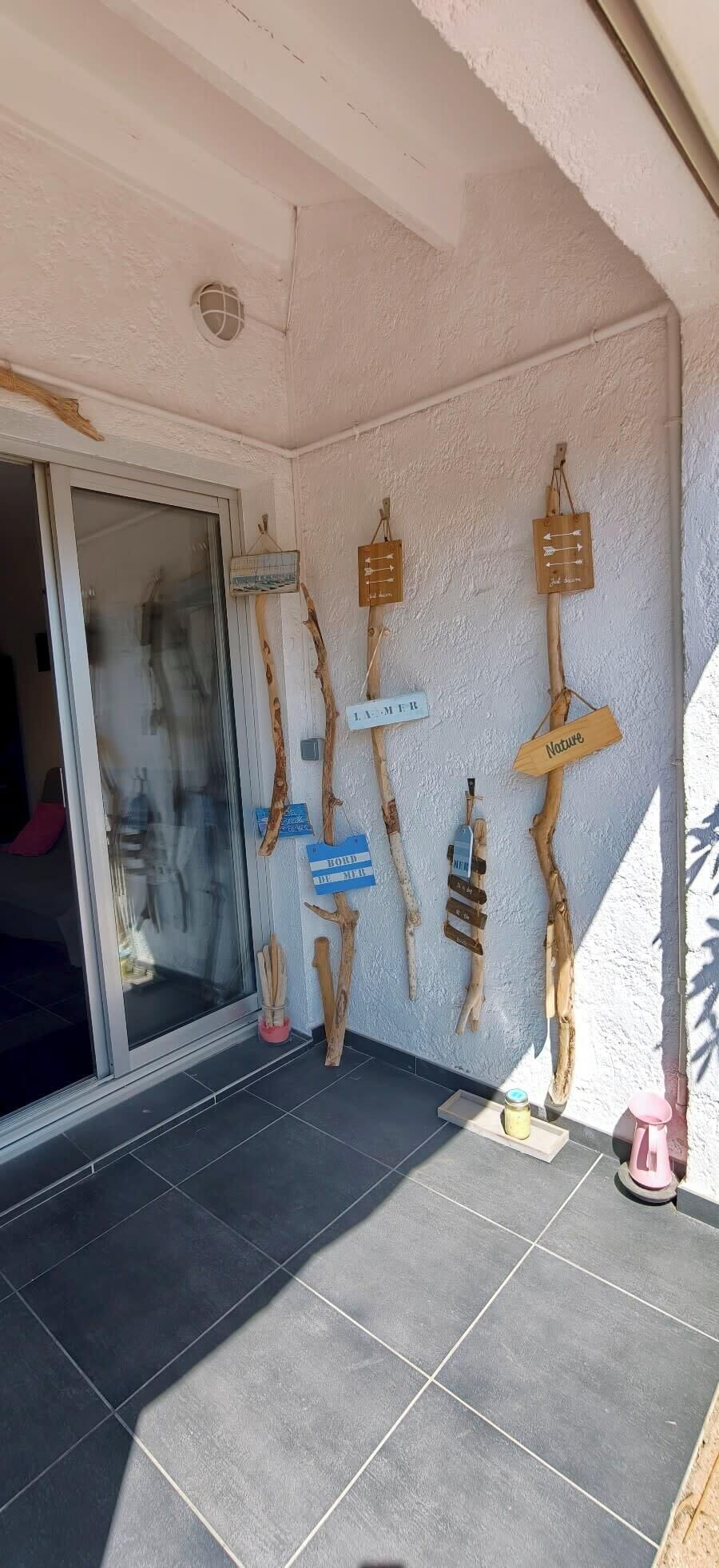 A room with a glass door, a tiled floor, and wall-mounted wooden signs with text.