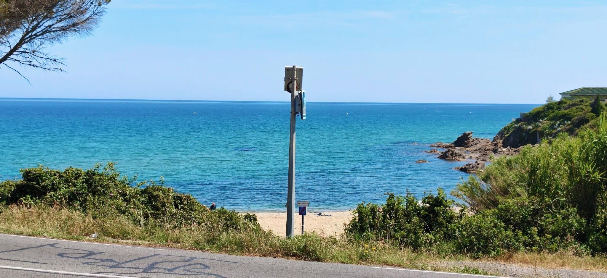 A coastal road with a clear view of the sea and a beach.