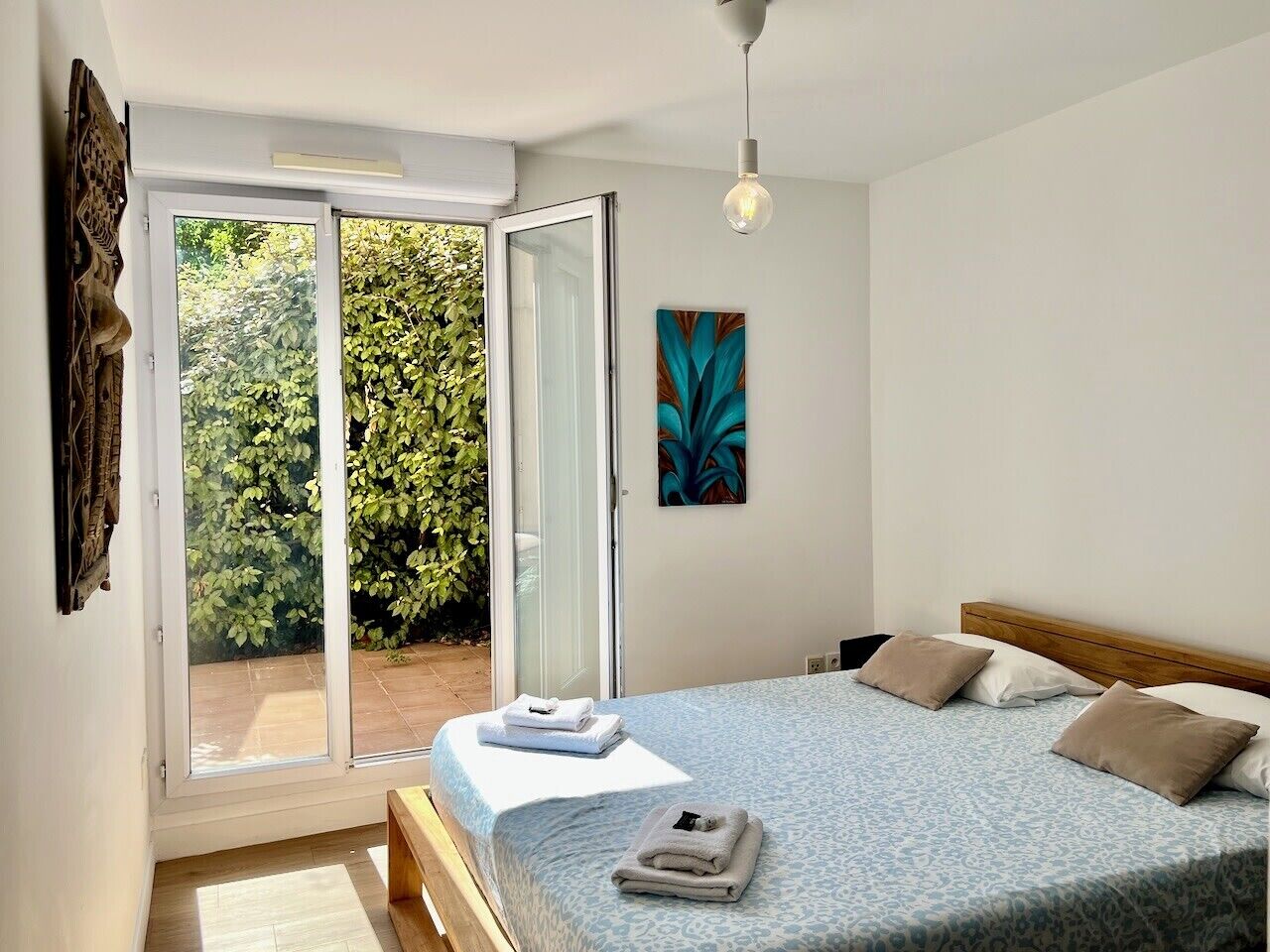A bedroom with a bed, a window, and a door leading to a balcony.