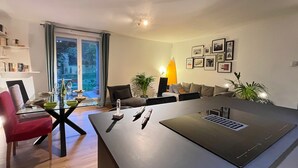 Una sala de estar moderna con una isla central, un comedor con una mesa de vidrio y un ventanal con vistas.