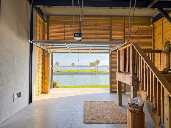 A modern interior with a view of a lake, a wooden staircase, and a welcome sign.