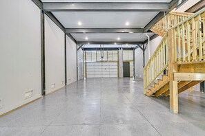 En rummelig indretning med et slejfet gulv, en trappe i træ og et loft med metalramme.