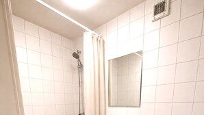 A bathroom with a shower, sink, toilet, and a mirror. - Java inspired Flat near Central St. (Aalborg)
