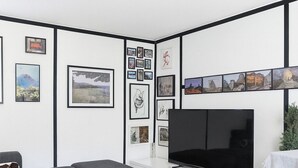 A modern living room with a flat-screen TV, grey sofa, white coffee table, and a wall decorated with framed pictures. - Java inspired Flat near Central St. (Aalborg)