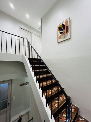 Eine Treppe mit schwarzen Geländern und gemusterten Stufen, die zu einer Zwischenebene führt.