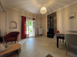 Ein geräumiges Wohnzimmer mit Kamin, Essbereich und einem roten Sessel.