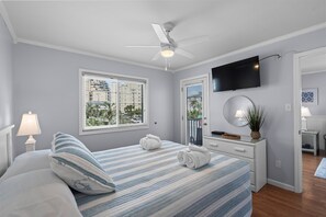 A bedroom with a bed, a ceiling fan, a TV, a window, and a bedside table. - Coastal Retreat Ocean and Pool Views 1st Floor (Murrells Inlet)