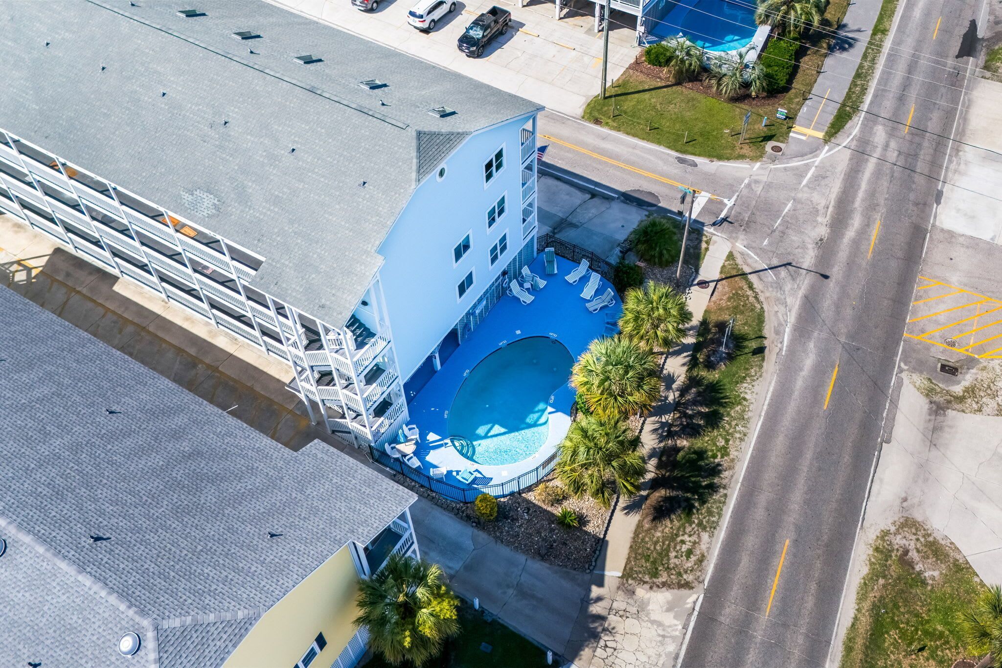 Oversigtsbillede af et hotel med swimmingpool, parkeringsplads og en vej.