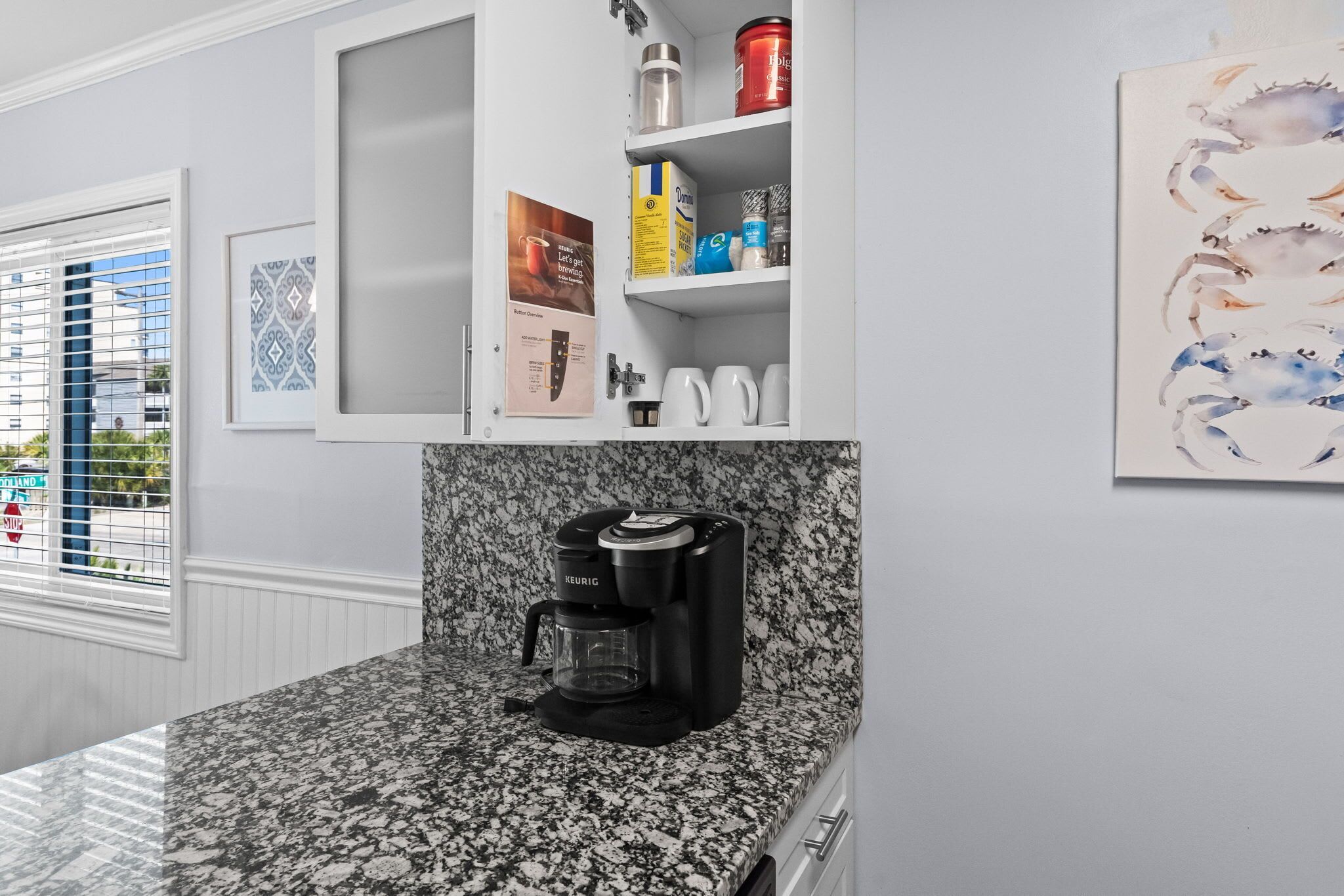 A kitchen with a Keurig coffee maker, a coffee station, and a cabinet with various items.