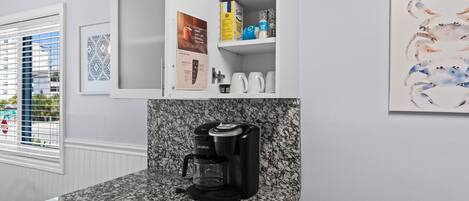 A kitchen with a Keurig coffee maker, a coffee station, and a cabinet with various items.