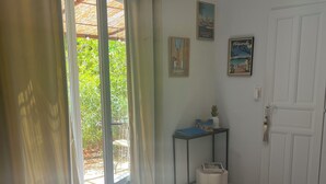 A room with a bed, a small table, a chair, a door, and a window with curtains.