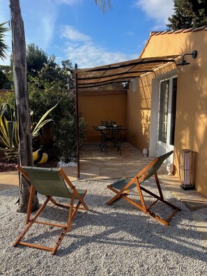 A patio with two folding chairs, a table, and a pergola.