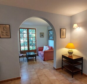 A living room with a sofa, a coffee table, a lamp, and a view through an archway to another room. - Villa Sainte Maxime, la Nartelle, 400 meters from the beach, sea view (Sainte-Maxime)