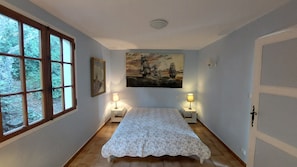 A bedroom with a bed, two bedside lamps, a painting, and a window with a view of trees. - Villa Sainte Maxime, la Nartelle, 400 meters from the beach, sea view (Sainte-Maxime)