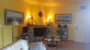 A living room with a fireplace, a dining table with chairs, a bookshelf, and two paintings on the walls. - Villa Sainte Maxime, la Nartelle, 400 meters from the beach, sea view (Sainte-Maxime)