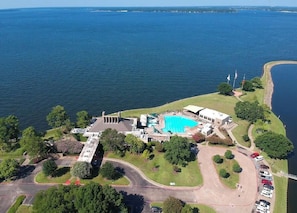 Oversigtsbillede af et resort med swimmingpool, en stor bygning og en parkeringsplads.